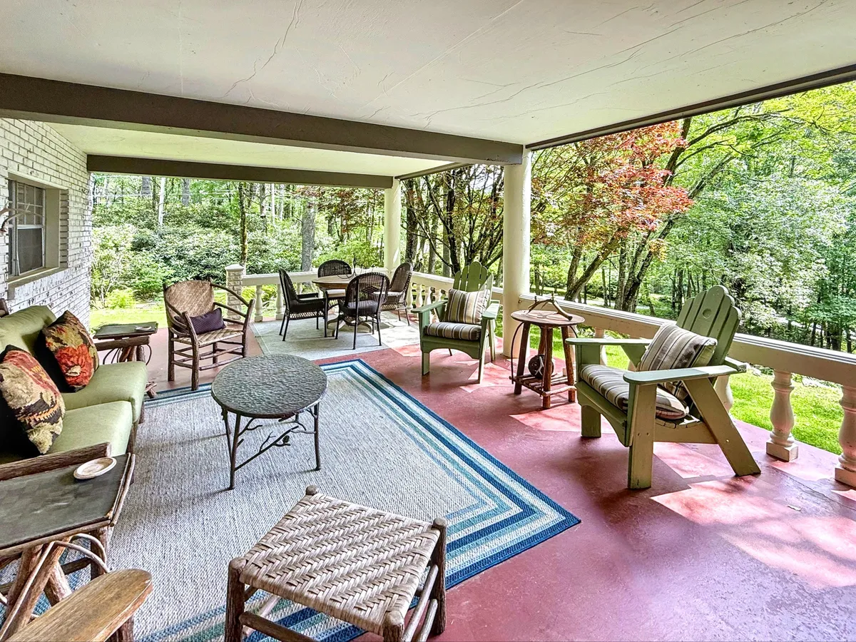 An outdoor dining area with a comfortable seating arrangement and table, surrounded by lush greenery. The tranquil, open-air environment is ideal for enjoying meals while immersed in nature.