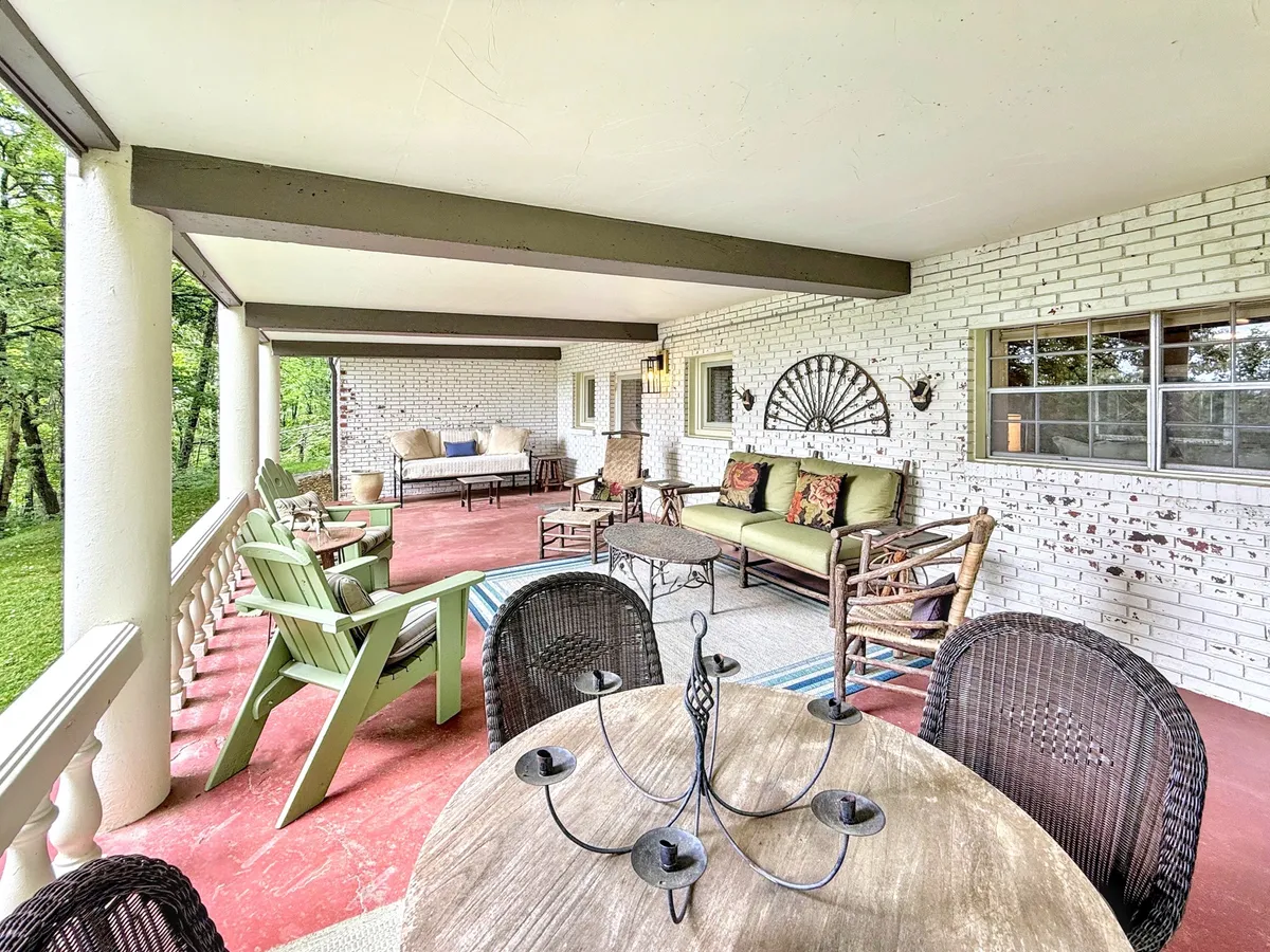 A welcoming outdoor seating area featuring a wooden dining table set amidst comfortable chairs, surrounded by decorative wall elements and open to views of nature. The space is clearly designed for relaxation and entertaining, suitable for both casual gatherings and alfresco meals.