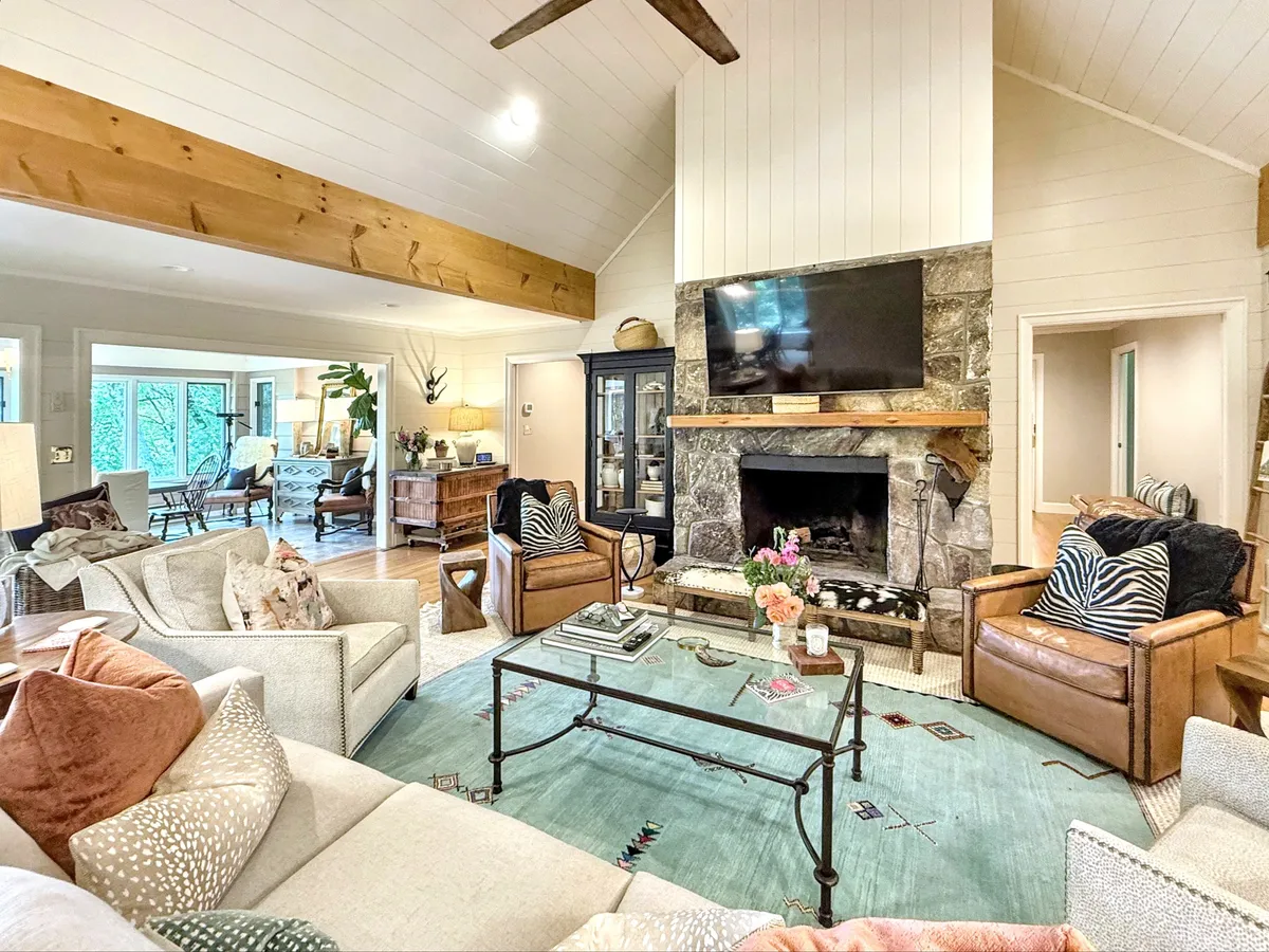 A spacious living room featuring a prominent fireplace as its centerpiece, surrounded by a comfortable sofa and armchairs. The room is thoughtfully decorated with inviting accents, creating a warm and welcoming setting ideal for family gatherings or quiet relaxation by the fire.